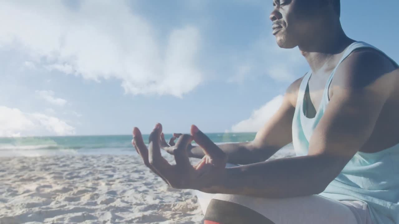 Animation of clouds over exercising african american man doing yoga on beach