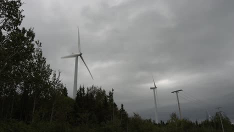 dos turbinas eólicas producen electricidad cerca de una línea eléctrica