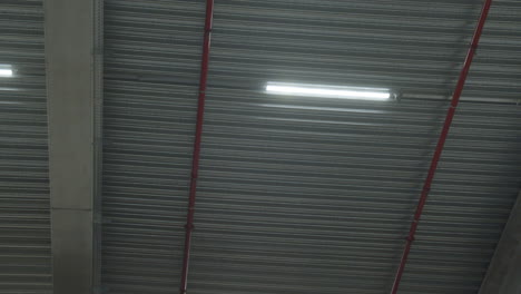 low angle pan of fluorescent lights hanging on industrial ceiling