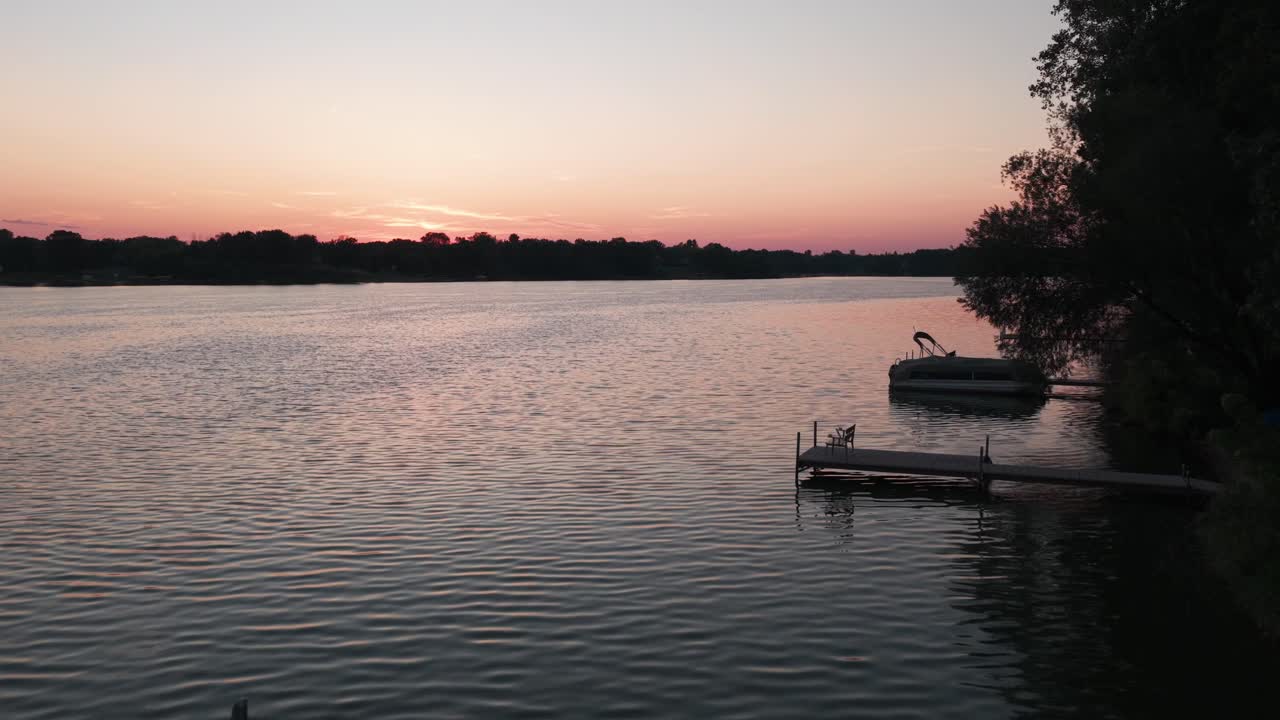 Low aerial shot flying over docked fishing and pontoon boats at sunset on a lake in Center City, Minnesota. 4K