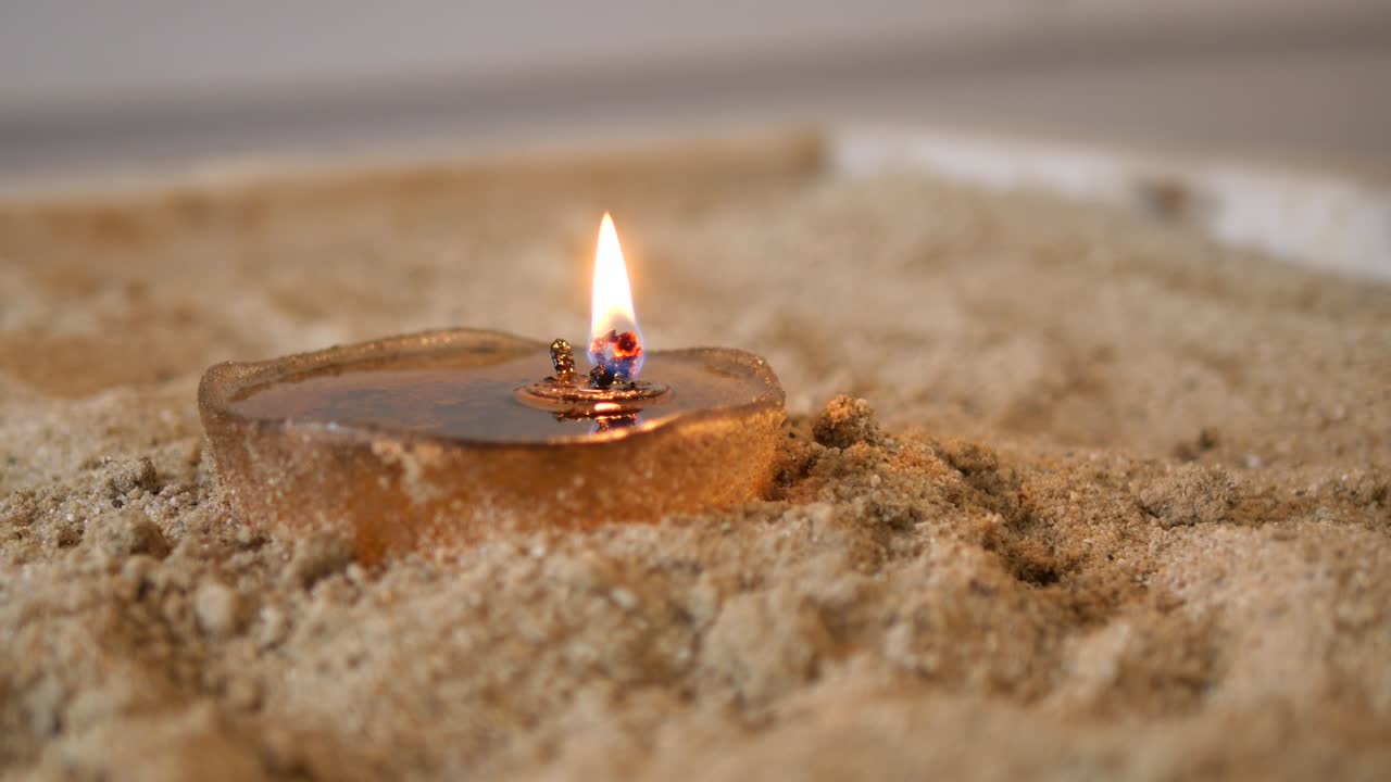 Close-Up of a Burning Oil Lamp in Sand