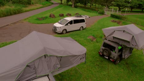 drone image pulling away, unveiling 3 campervans in a camping site in bijagual, costa rica