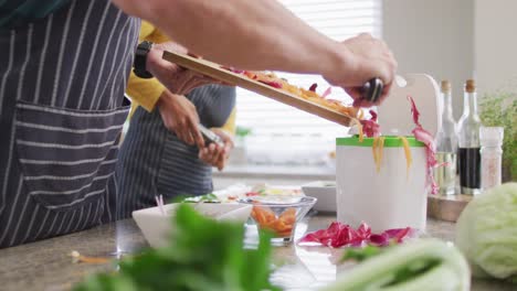 video of midsection of diverse couple preparing meal, drinking wine and having fun in kitchen