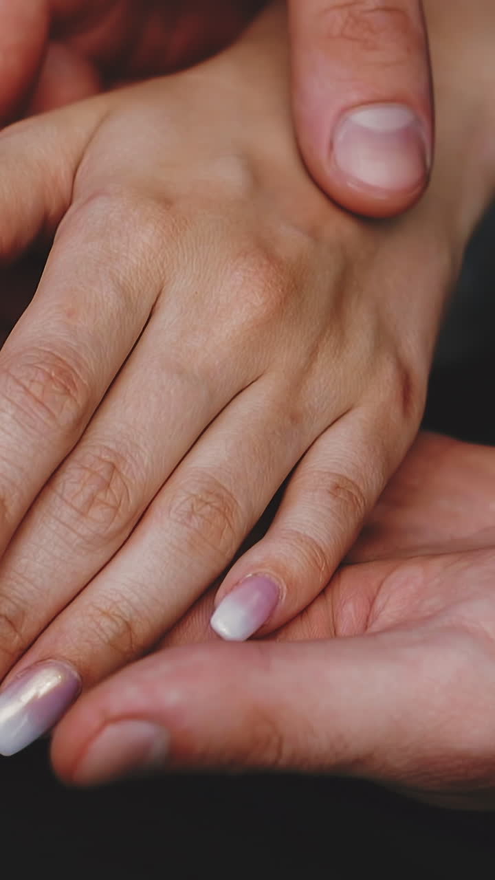 CU, slow motion: careful young groom wearing dark suit holds stroking hand of future wife in elegant white dress sitting together extreme close view