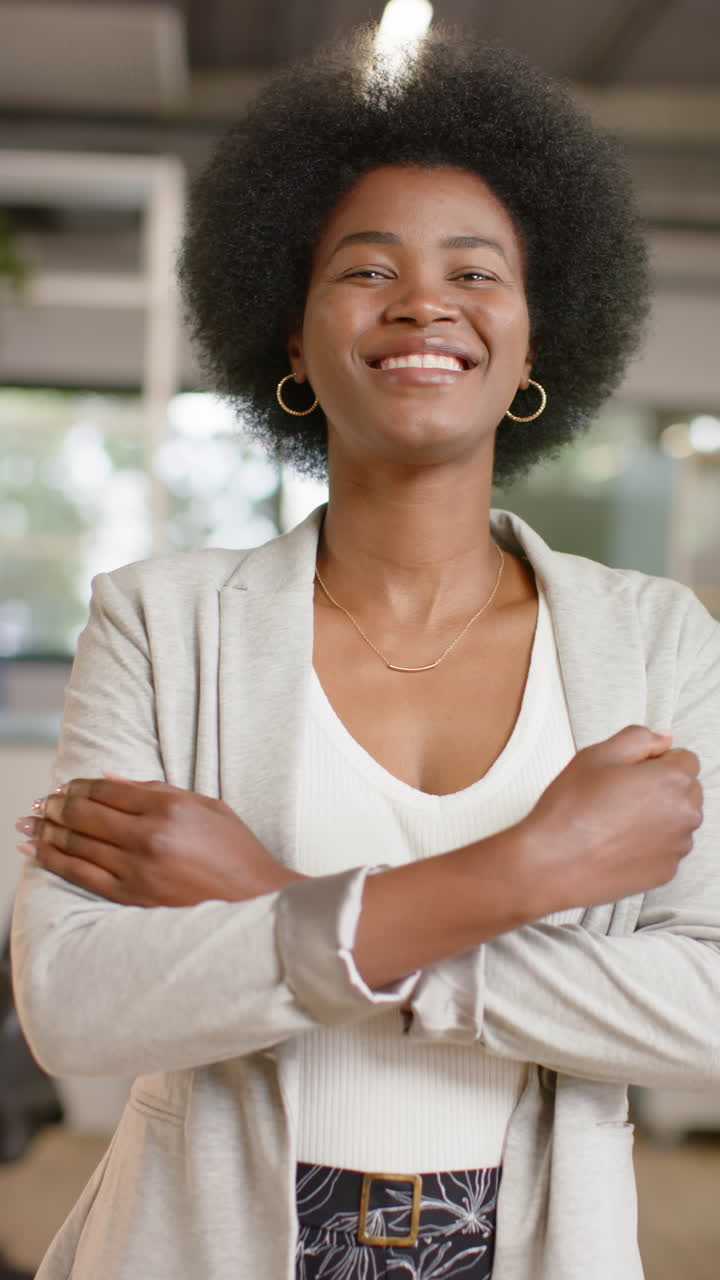 Vertical video of portrait of happy african american casual businesswoman in office, slow motion