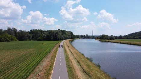 Group-of-people-cycling-on-a-trail-next-to-a-river-Morava,-Czech-Republic-4K