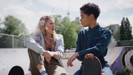 two female friends talking and laughing in urban skate park