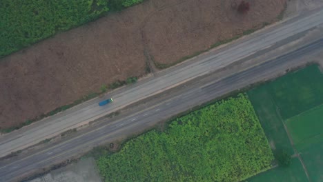 vista aérea de pájaro sobre la autopista a través de las tierras de cultivo de sindh con el tráfico pasando