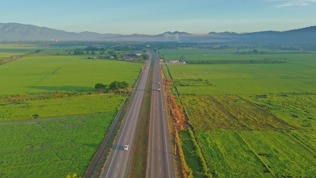 Drone flying over Duarte highway, countryside, green rice fields, Bonao, Dominican Republic. Aerial forward