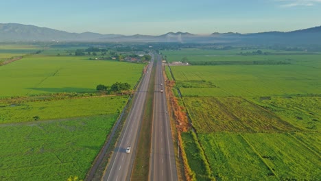 drone flying over duarte highway, countryside, green rice fields, bonao, dominican republic. aerial forward
