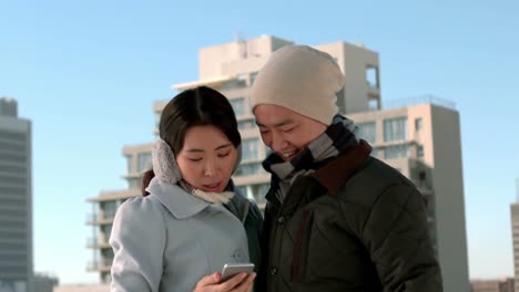 couple in warm clothes using mobile phone