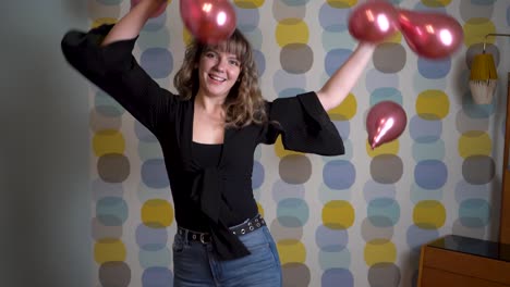 mujer joven bailando frente a globos flotantes en el aire contra un fondo colorido