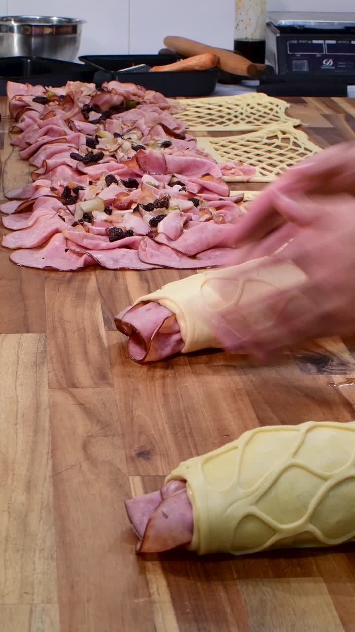 Preparazione e arrotolamento del pan de jamon su un bancone di legno in una cucina accogliente.