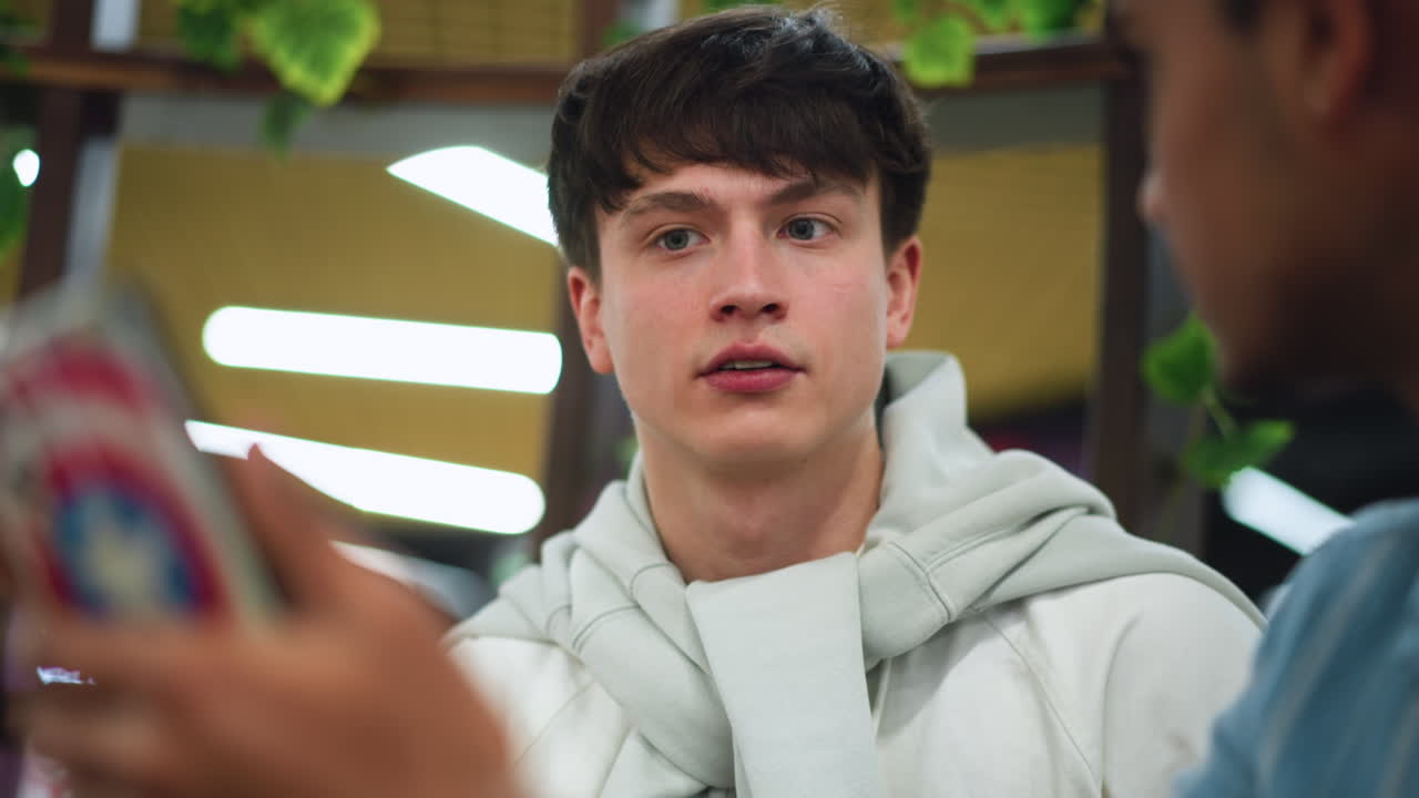 Male adult in blue shirt boldly explaining content to companion while companion nods in agreement and conviction close conversation in modern indoor setting showing trust and understanding