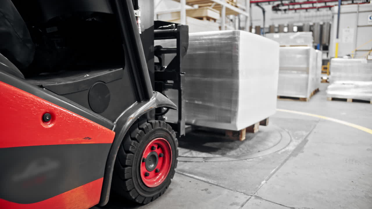 Carrello elevatore che trasporta un pallet imballato all'interno di un magazzino.