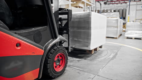 forklift carrying a wrapped pallet inside of a warehous