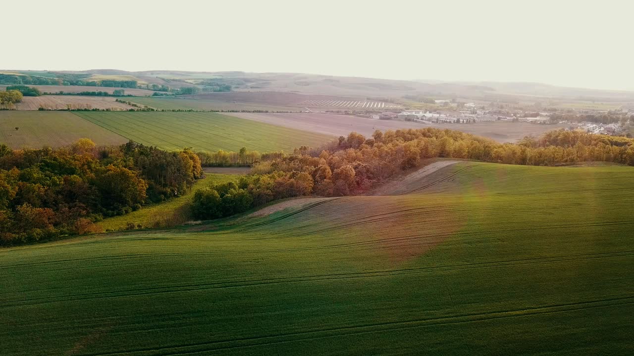 Stunning Aerial View of Rolling Green Hills and Farmland at Sunset