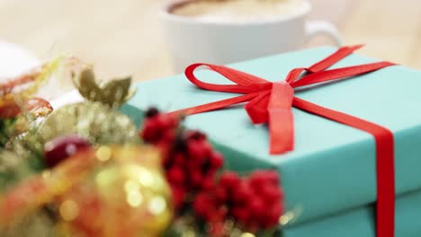 Close-up-of-coffee-cup-with-christmas-decoration-and-gift