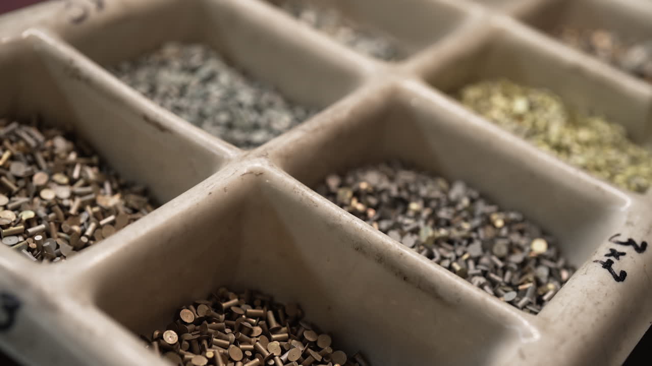 Worker sorting small metal parts for rivets in an organized production facility for manufacturing