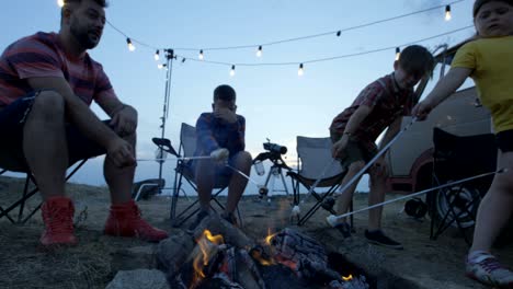 laughing family frying marshmellow on bonfire