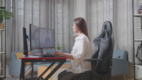 vista lateral de una diseñadora automotriz asiática teniendo una reunión con una mujer mientras trabaja en un modelo 3d de un coche ev en las computadoras de escritorio en el estudio