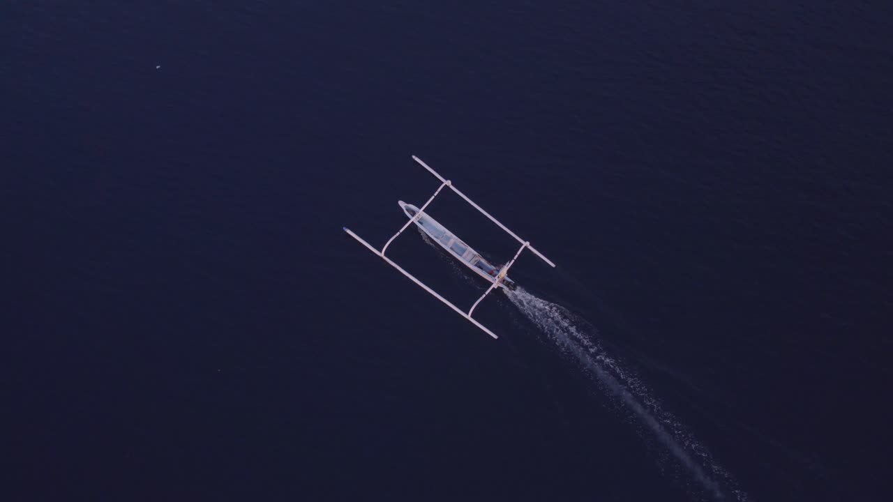 Top down view of traditional fishing boat cruising in the ocean at Bali indonesia, aerial
