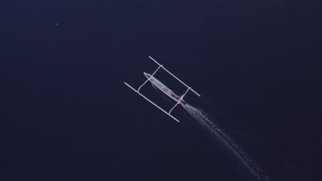 Top-down-view-of-traditional-fishing-boat-cruising-in-the-ocean-at-Bali-indonesia,-aerial