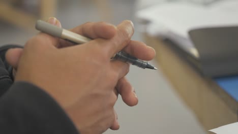 manos masculinas sosteniendo un bolígrafo pensando en el espacio de la oficina