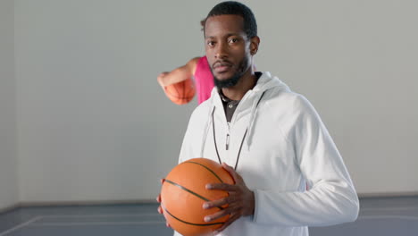 african american coach holds a basketball in an indoor court