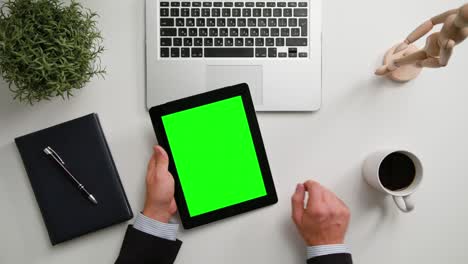 las manos de un hombre sosteniendo una tableta digital con una pantalla verde
