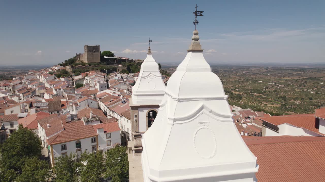 산타 마리아 다 데베사 교회의 종탑과 배경에 있는 오래된 성 주변을 공중으로 도는 공중, 포르투갈의 카스텔로 데 비데