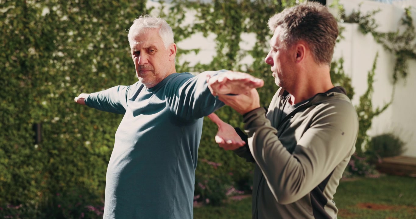 Physical Therapist Assisting Senior Man with Arm Stretching Exercise
