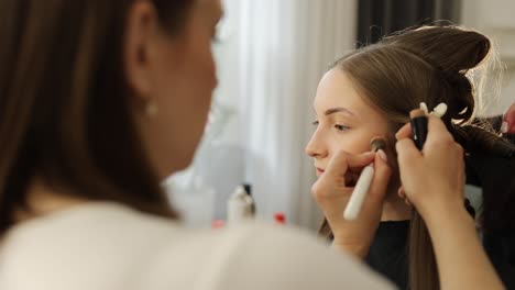 skilled beauty expert applies makeup on a model using modern techniques and styles