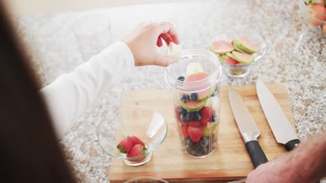 Midsection-of-caucasian-couple-preparing-heathy-smoothies-in-kitchen,-slow-motion