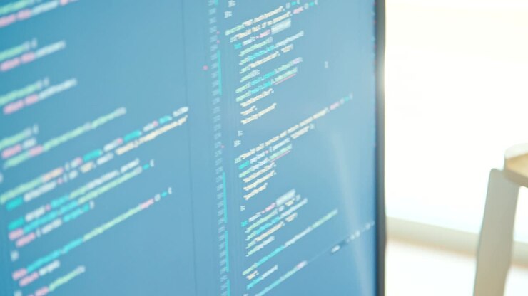 En computerprogrammør sidder foran en skærm og koder software.