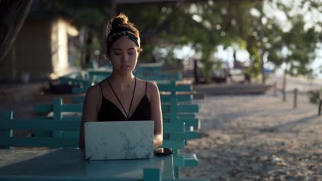 Chica-Independiente-Pensando-En-Su-Próxima-Publicación-En-Las-Redes-Sociales-En-Una-Computadora-Portátil-En-La-Playa,-Bali