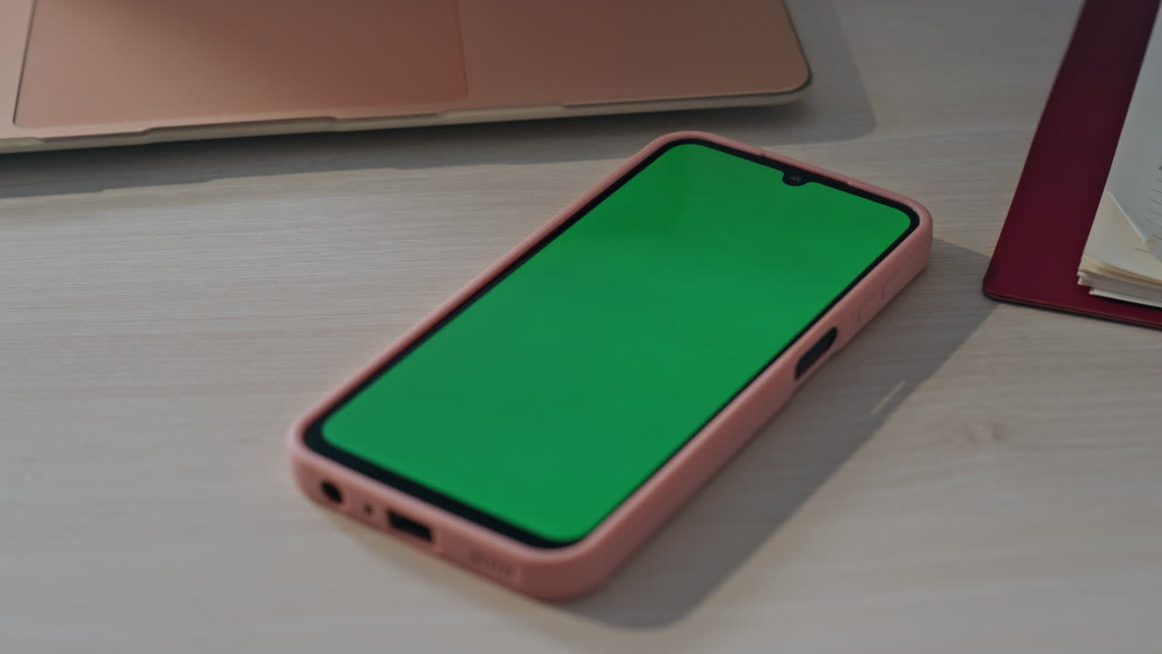 Green screen smartphone lying at empty workplace close up. Chroma key cellphone