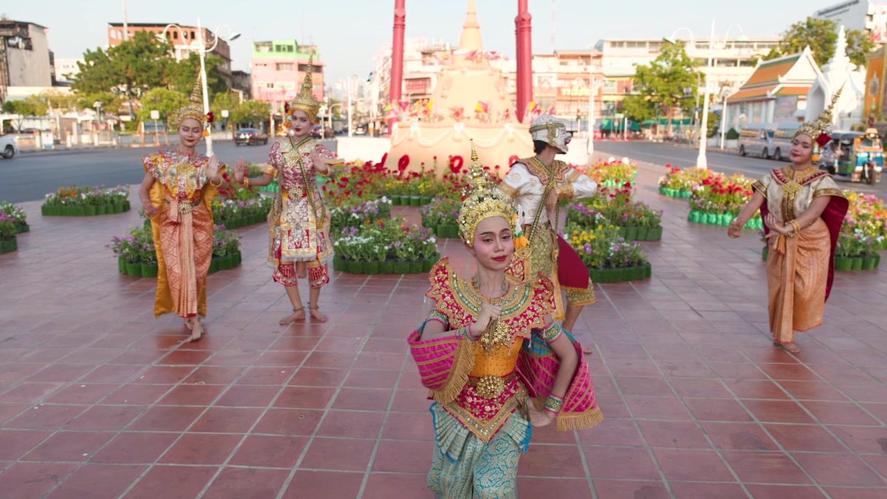 Penari tradisional Thailand dengan kostum berhias menampilkan koreografi Manohra klasik di luar ruangan di Wat Suthat.