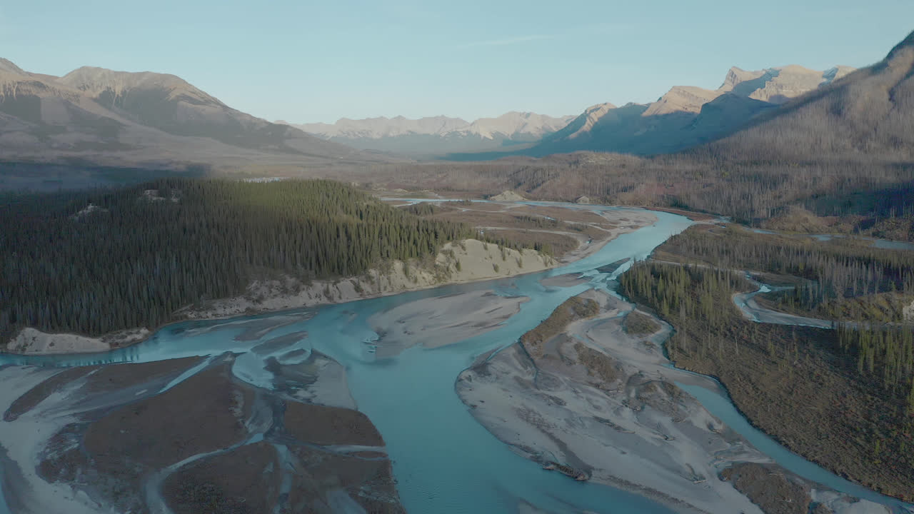 vista aérea del arroyo en medio del bosque con la cordillera rocosa en el fondo en verano en alberta, canadá