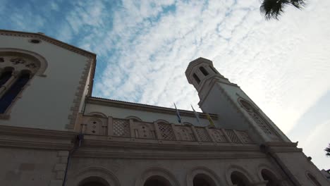 Blick-Von-Unten-Auf-Die-Seitliche-Fassade-Der-Kathedrale-Von-Agia-Napa-Unter-Bewölktem-Sommerhimmel---Weitwinkelschwenk