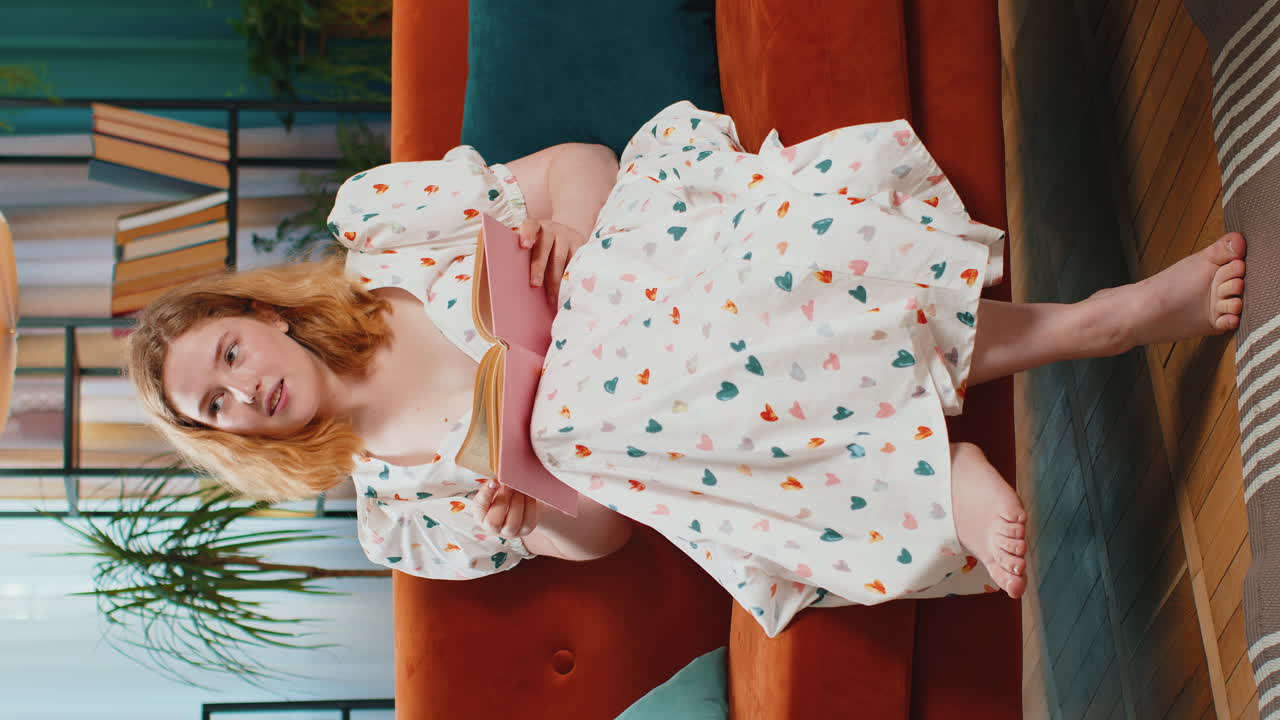 Redhead woman relaxing interesting book turning pages smiling enjoying literature taking a rest