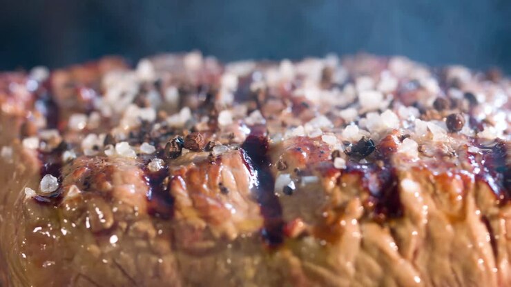 arge steak is grilled, there is smoke from the coals to the meat, side view, close-up shot 4ksteak steak with a very tasty view 4K