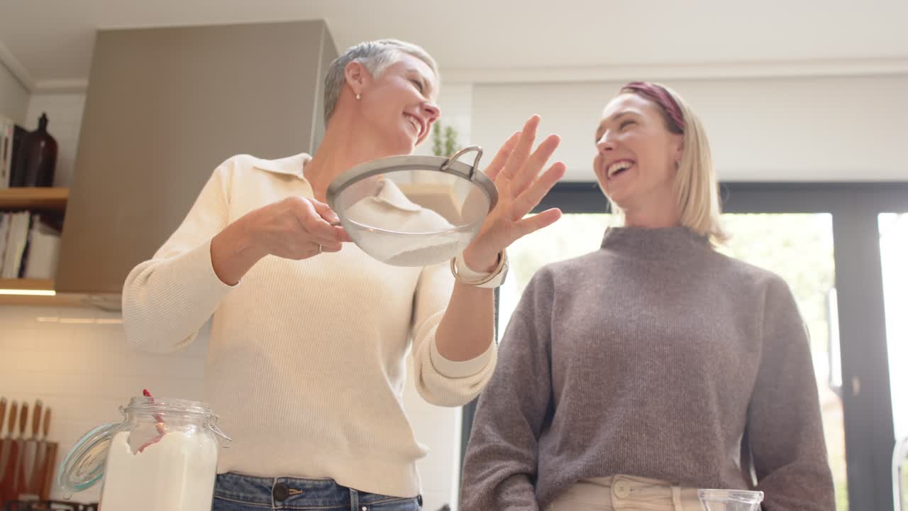 Mor og datter henter si og sier mel i røreskål i køkkenet, mens de bager