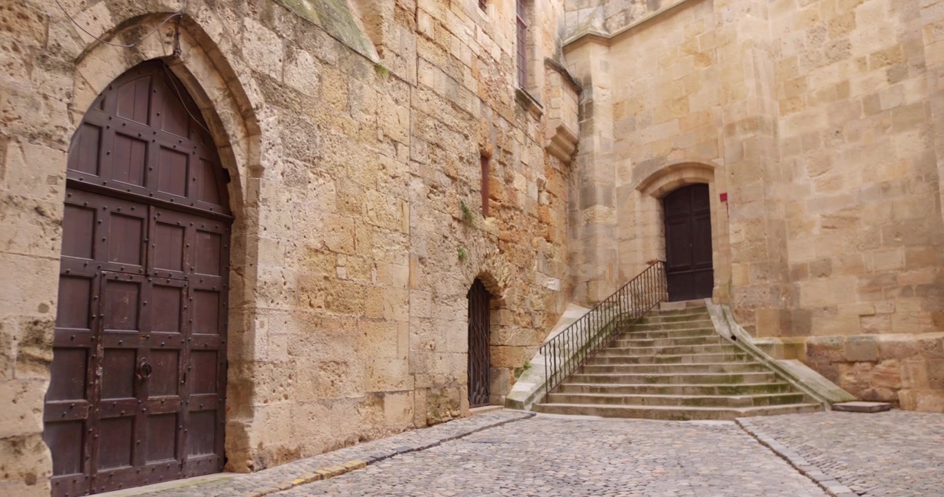 Mura in pietra medievali, porta in legno ad arco gotico e scala in pietra presso il Palazzo Arcivescovile a Narbonne, nel sud della Francia.