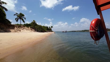 Slow-motion-action-camera-shot-from-on-board-of-a-small-tourist-boat-docked-on-the-tropical-Restinga-beach-near-Barra-do-Cunhaú-in-Rio-Grande-do-Norte,-Brazil-on-a-warm-sunny-summer-day