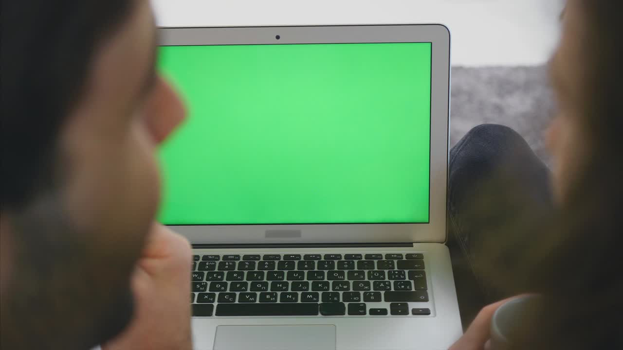 amando a la joven familia juntos. hermosa pareja joven. relación amorosa entre sí y mirando una computadora portátil con una sonrisa mientras están sentados en el sofá juntos.