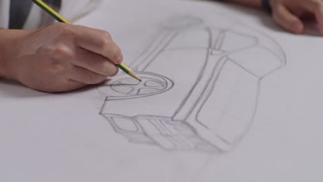 close up of male's hands drawing new car concept on a paper on the table in the studio