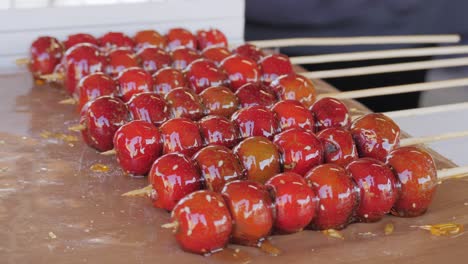 making fruits in boiling caramel close-up. chinese winter sweet dessert tanghulu street food.berries, grapes, tangerine and others fruit caramelized in sugar. asian street market with traditional food.. high quality 4k footage