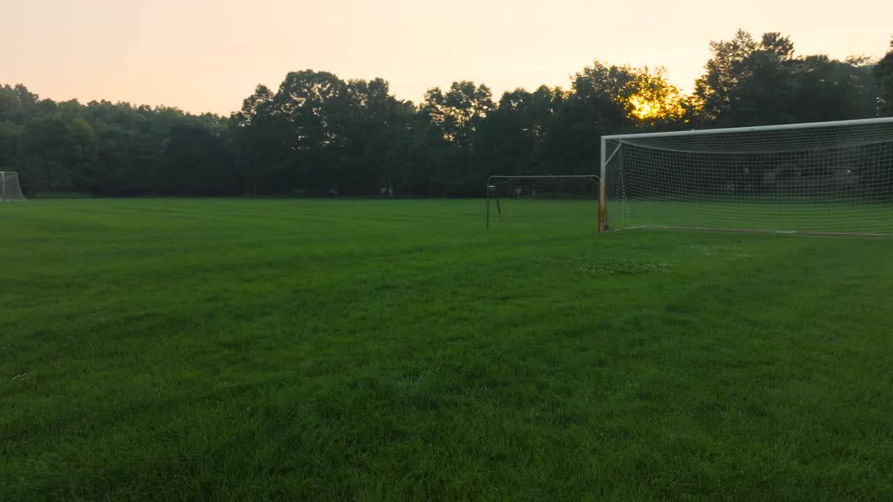 толкает к футбольным сетям, разбросанным по полю