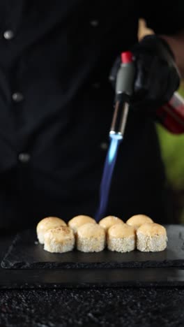 chef preparing sushi rolls with a kitchen torch